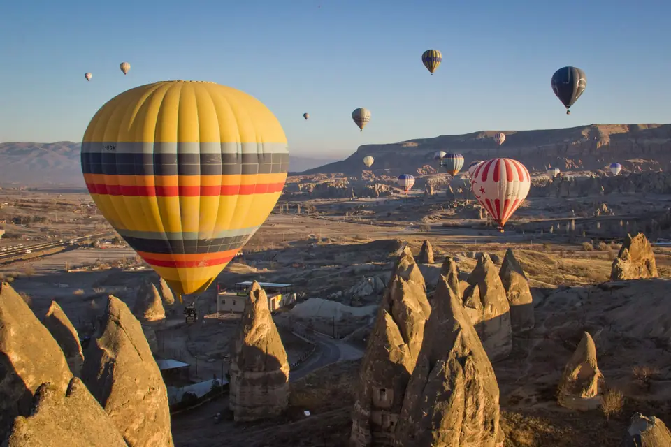 Balloon rising past fairy chimneys at sunrise