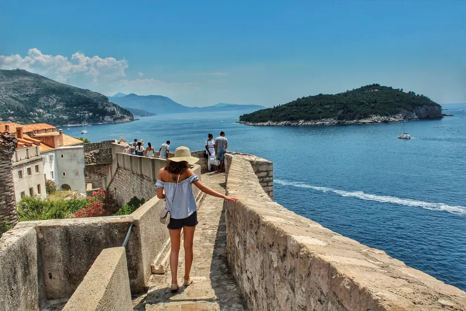Visitor walking the Dubrovnik city walls with Lokrum island offshore