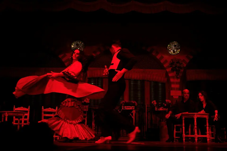 Flamenco dancers in red dresses on a dark stage