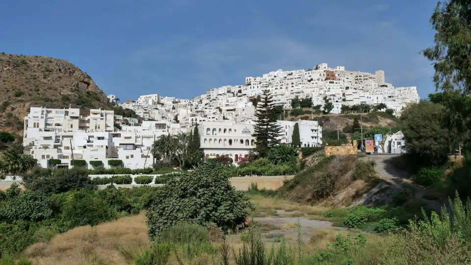 Whitewashed houses of an Andalusian hill town above green slopes