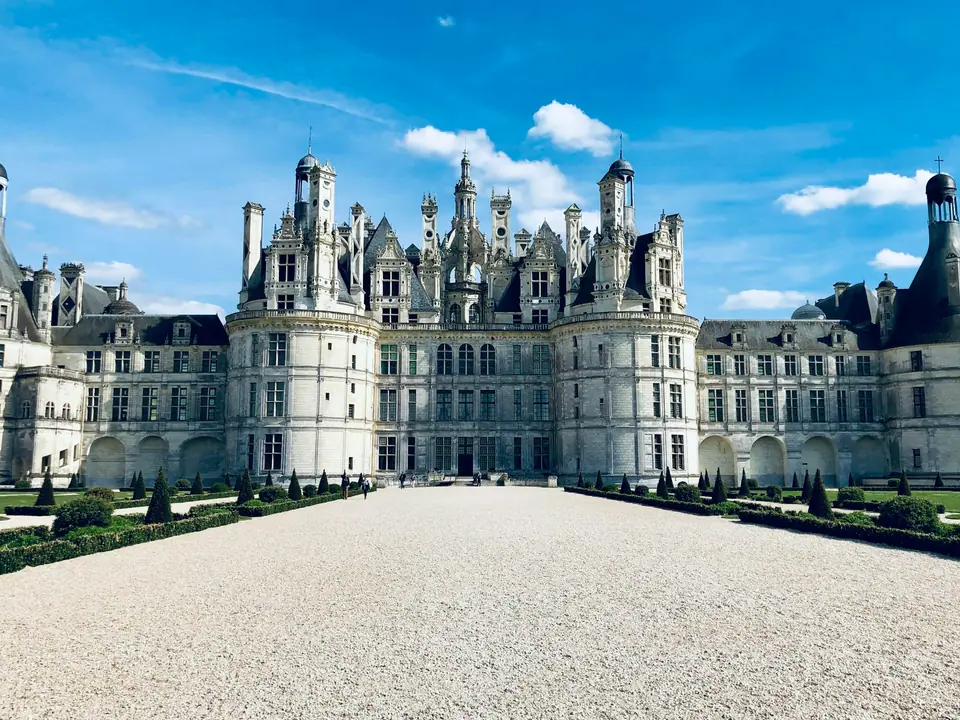 The white Renaissance château of Chenonceau stretching across the River Cher on a series of arches, reflected in the calm water