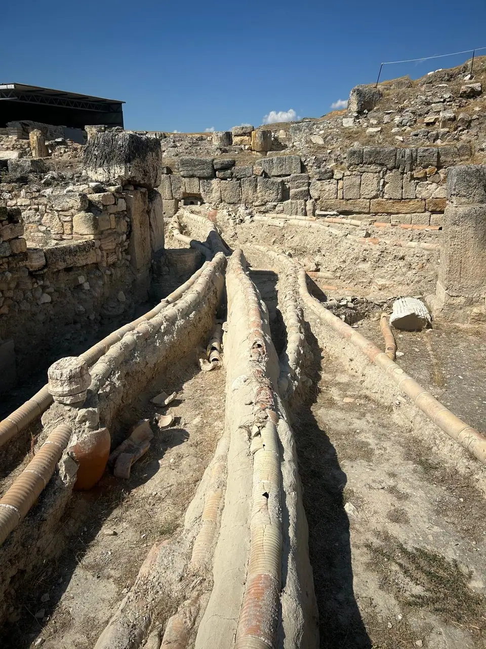 Rows of terracotta water pipes laid along a stone channel at Tripolis