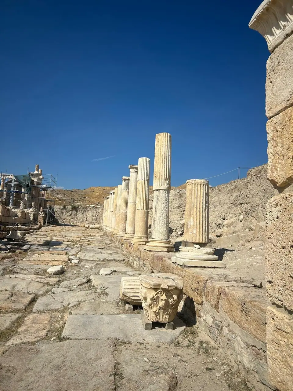 Colonnaded street at Tripolis with fluted columns and a fallen Corinthian capital on the paving