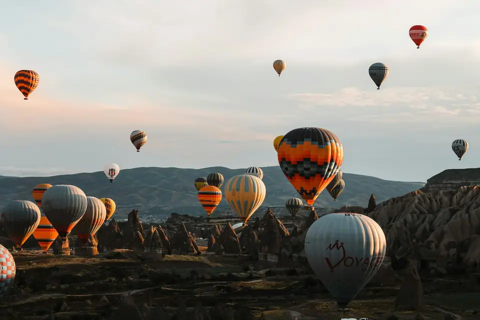 Dozens of colourful hot air balloons rising over the rock cones and valleys of Cappadocia at sunrise
