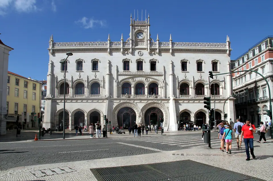 Rossio railway station façade with travellers outside in Lisbon