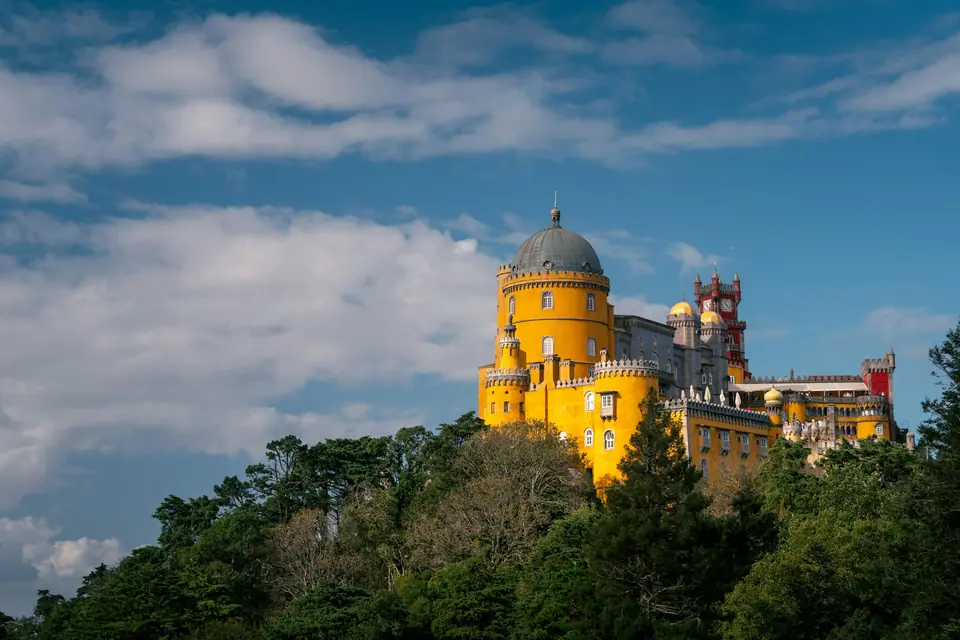 Yellow and red towers of Pena Palace above the forest in Sintra
