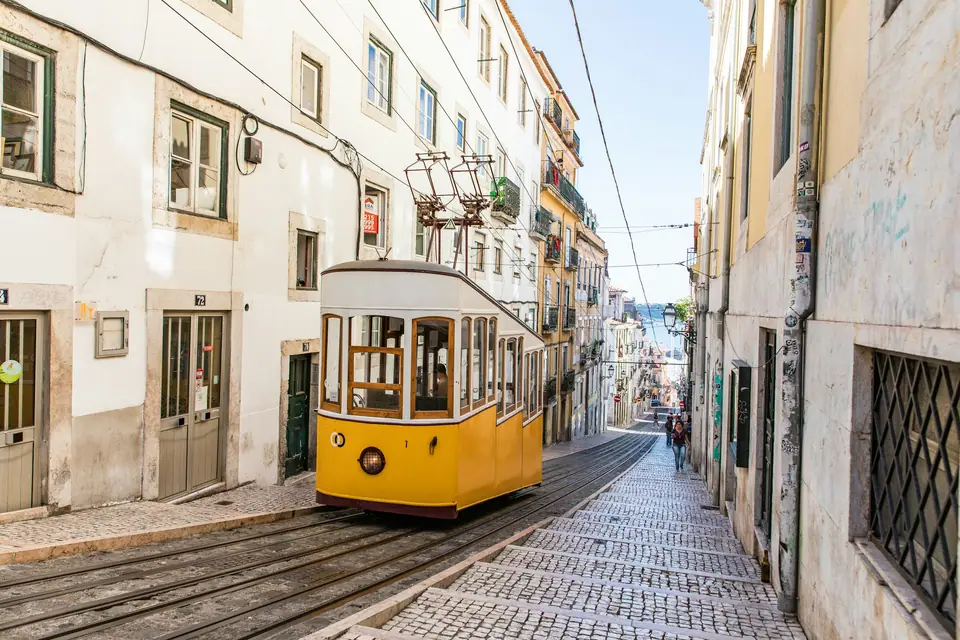 Yellow tram climbing a narrow cobbled street in Lisbon