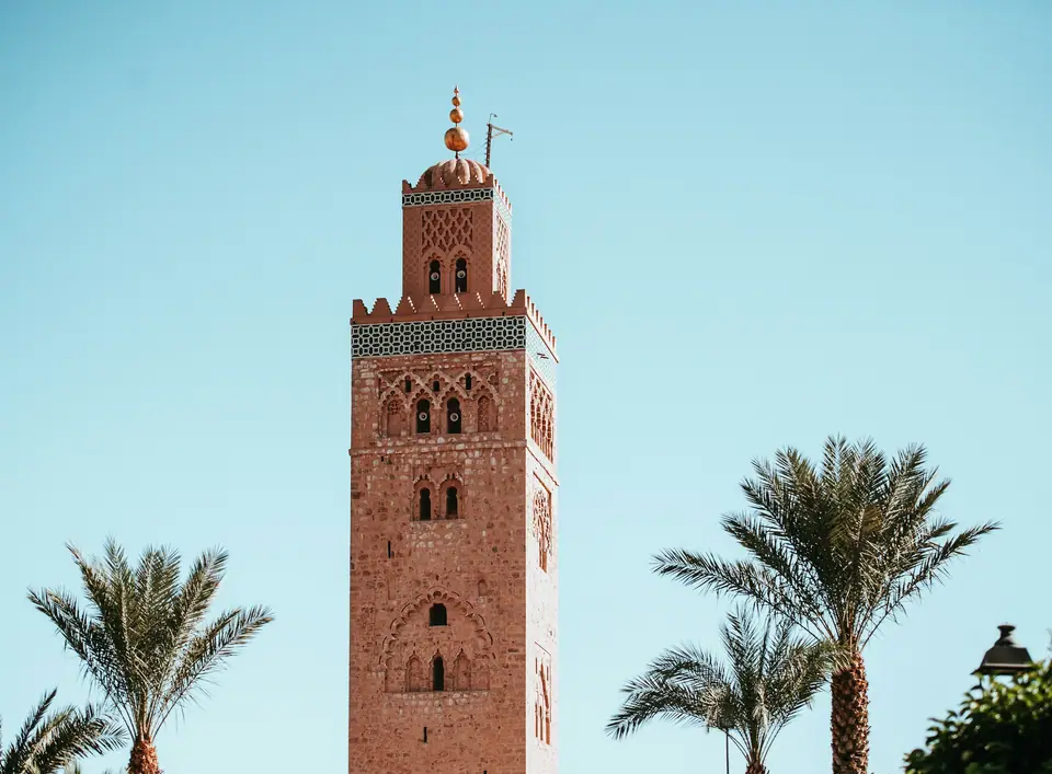 Koutoubia minaret between palm trees against a blue sky