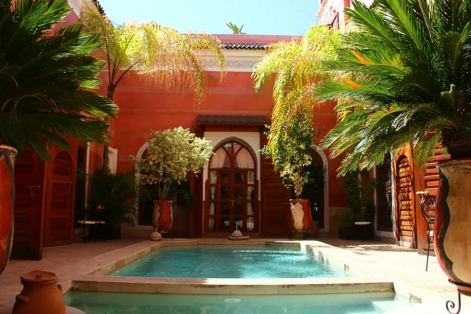 Courtyard pool of a riad surrounded by palms and arches