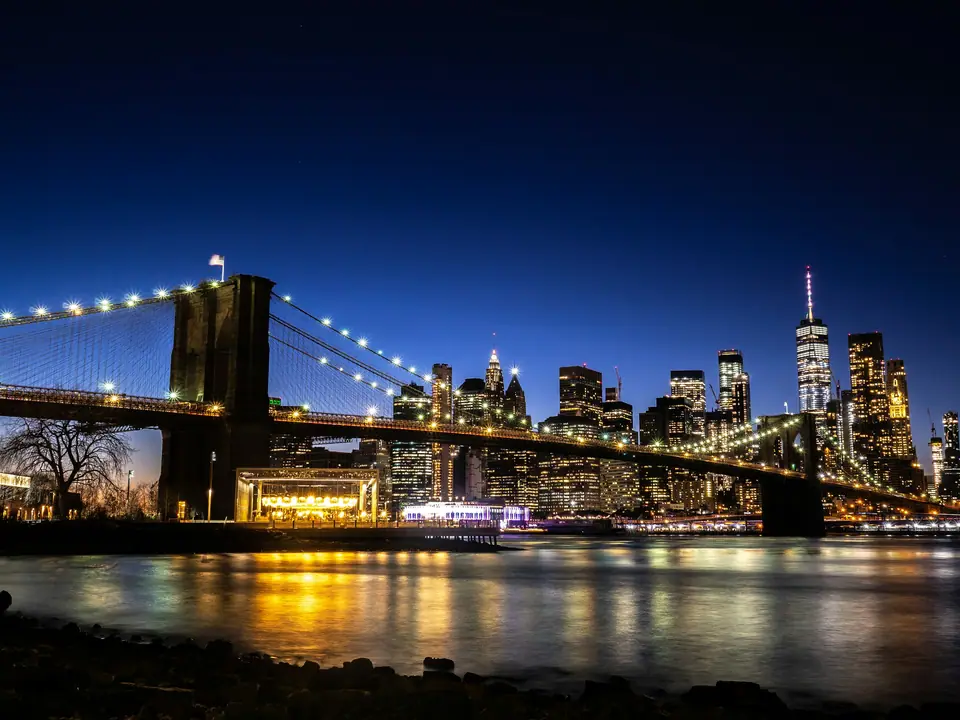 Brooklyn Bridge lit up at night with the Lower Manhattan skyline