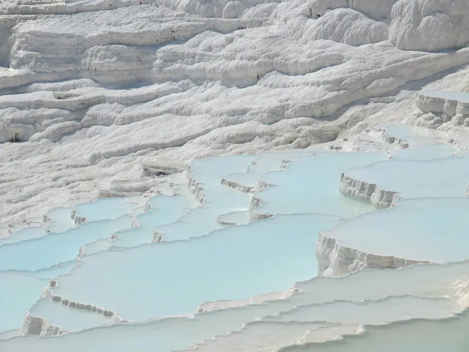 White travertine terraces of Pamukkale with the ruins of Hierapolis above